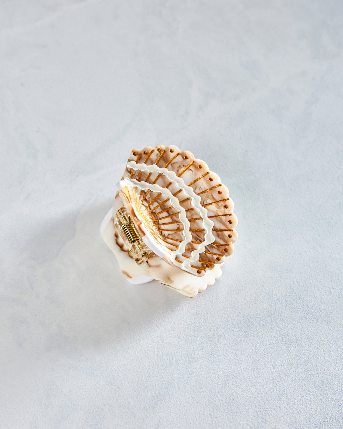 White shell-shaped claw hair clip with gold-painted details, shown from the back with its spring clasp visible.