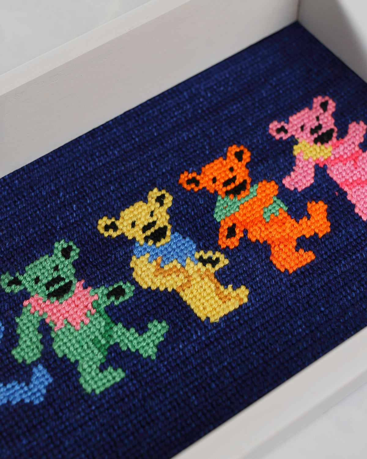 Close-up angled view of the dark navy valet tray’s stitched dancing bear design.