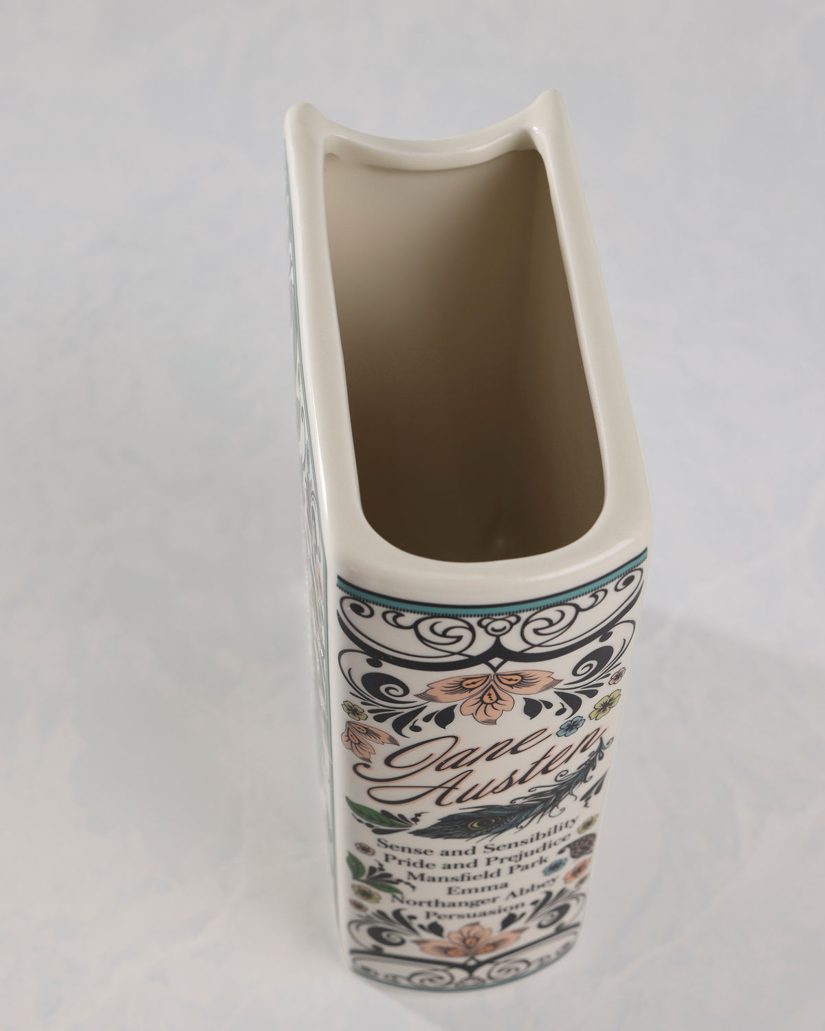 Top-down angled view of the open top of the Jane Austen book-shaped vase, with the floral side panel visible below.