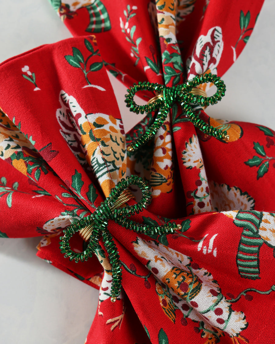 Green beaded bow napkin ring shown securing a folded patterned napkin
