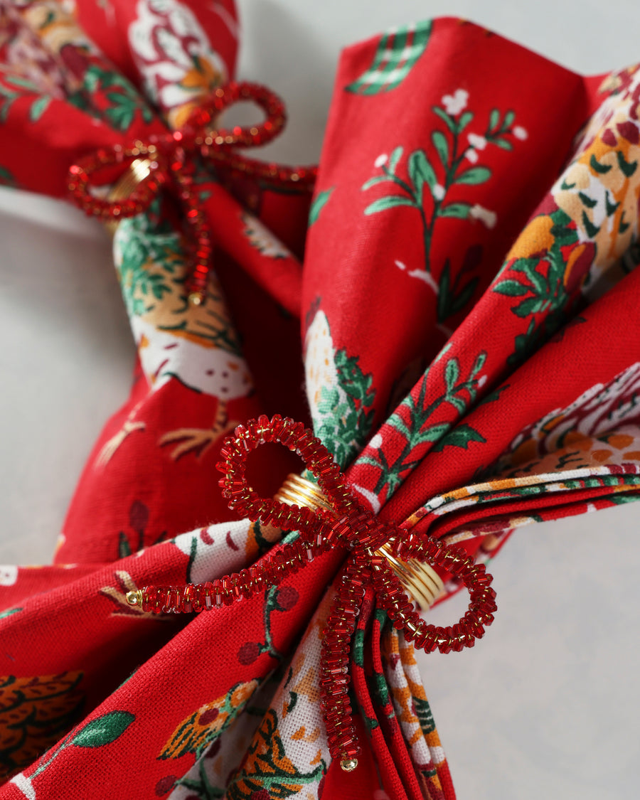 Close-up of a red beaded bow napkin ring around a folded patterned napkin