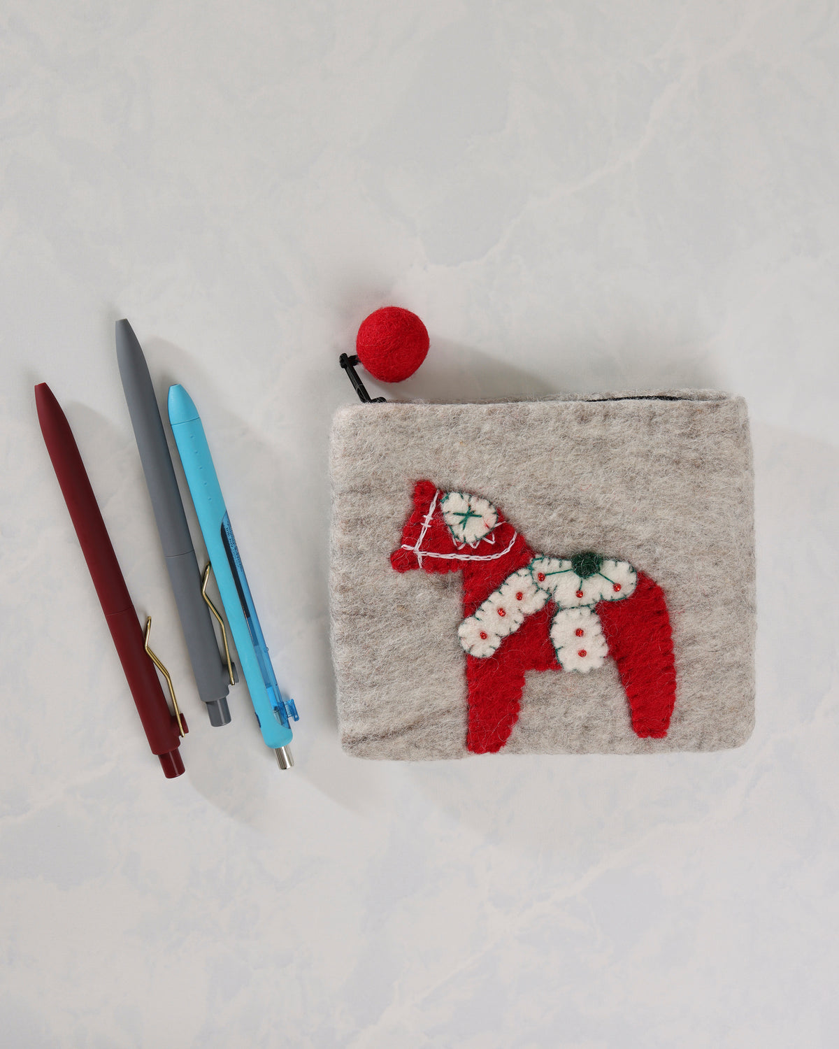Ivory Dala horse purse shown beside three pens, with a red felt horse applique and red ball zipper pull.