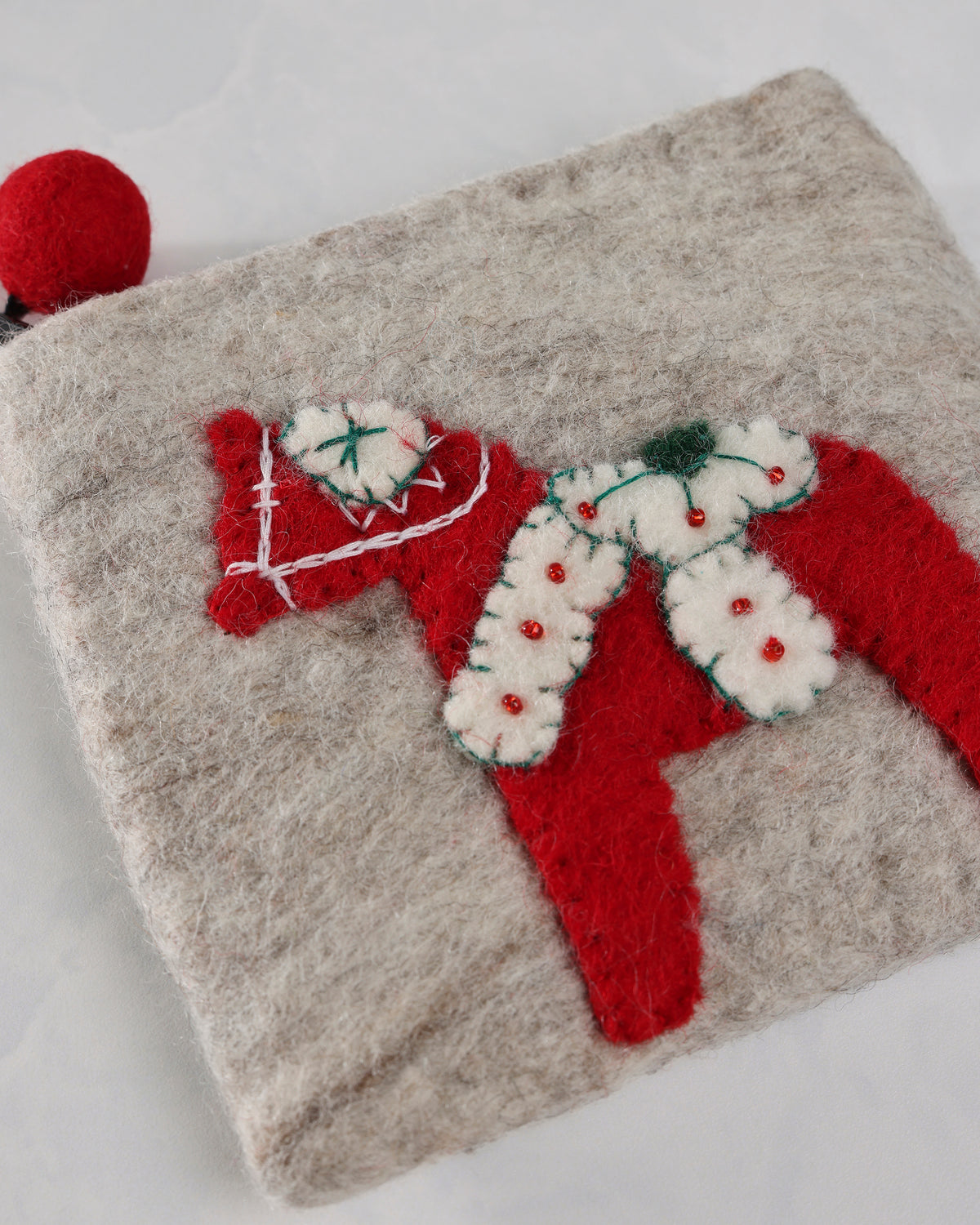 Close-up of the ivory Dala horse purse showing the red horse applique, stitched details, and red ball zipper pull.