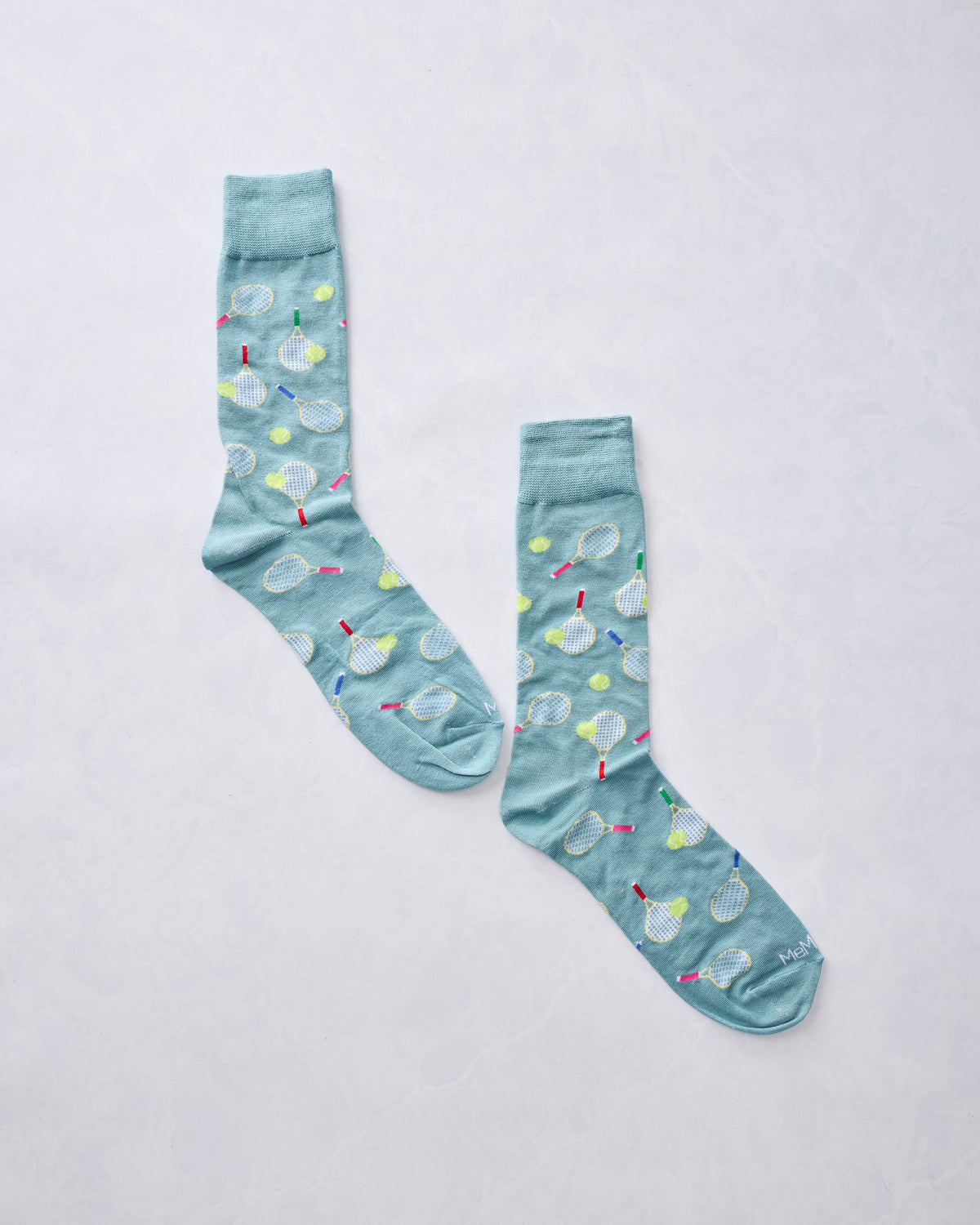 Pair of light blue crew socks covered with tennis-racket and tennis-ball illustrations.
