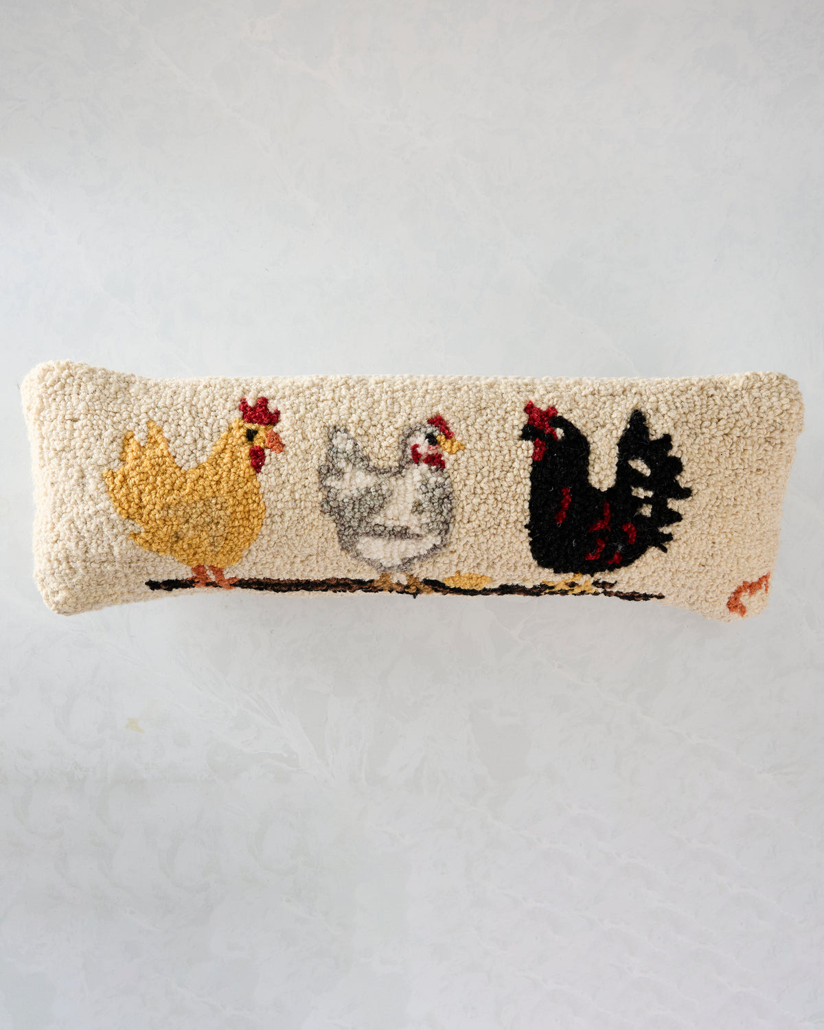 Front view of an ivory rectangular pillow with hooked artwork depicting three chickens perched on a branch.