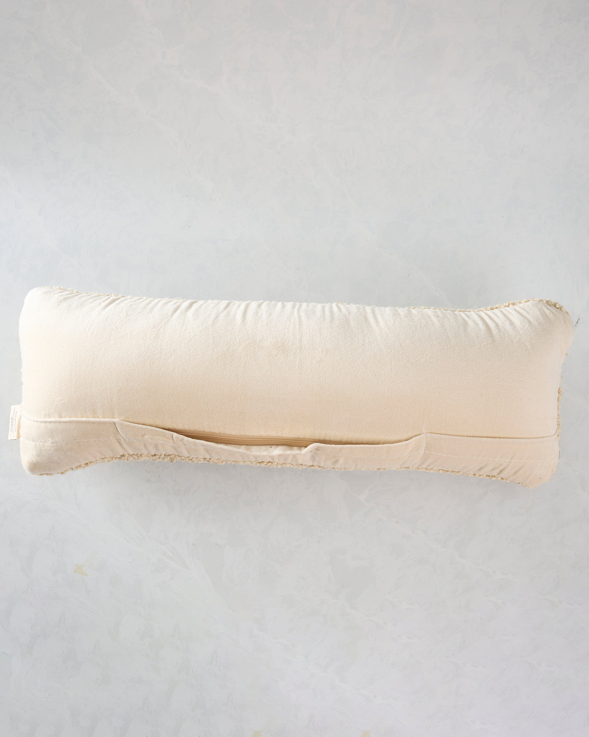 Back view of the ivory rectangular pillow showing its plain fabric back and concealed zipper.