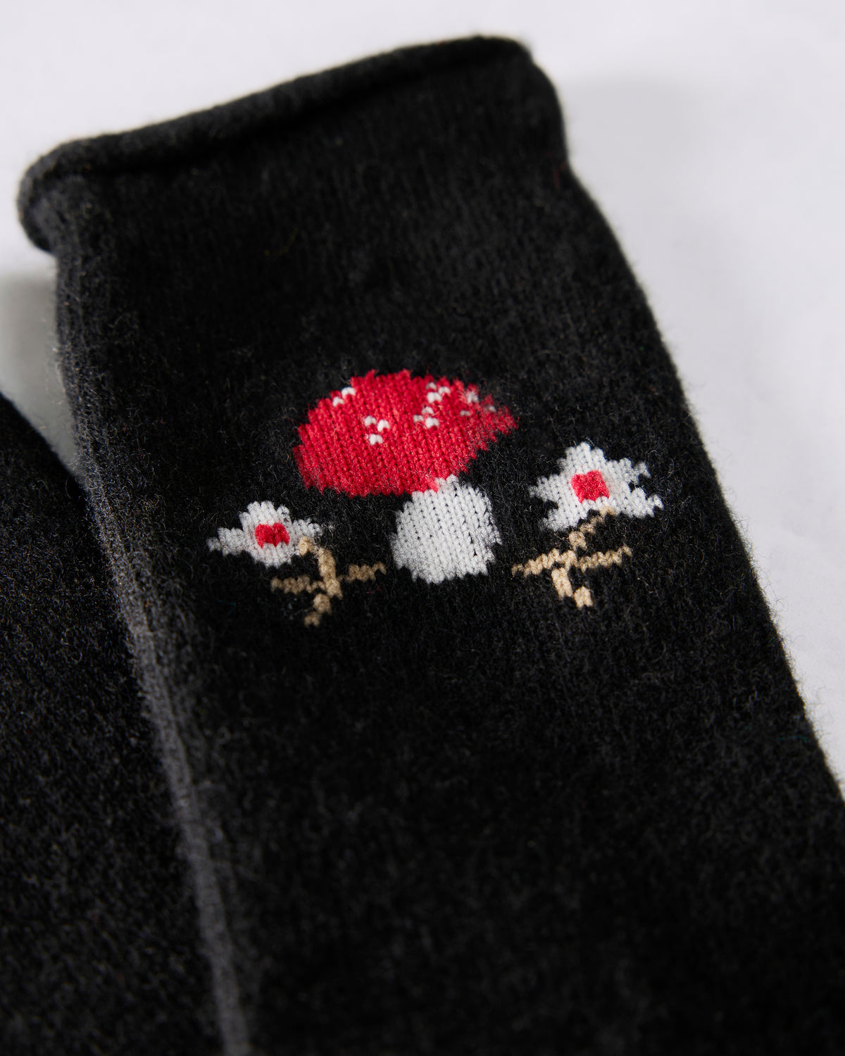 Close-up of a black crew sock showing its red-and-white toadstool motif.