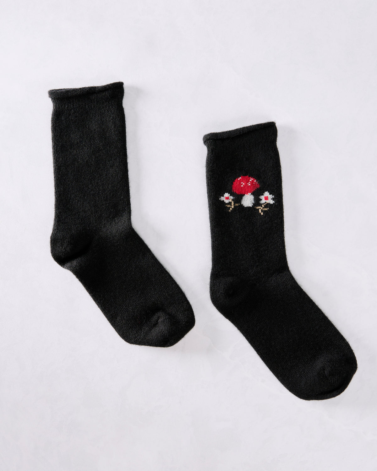 Two black crew socks displayed separately, with a red-and-white toadstool motif on one sock.