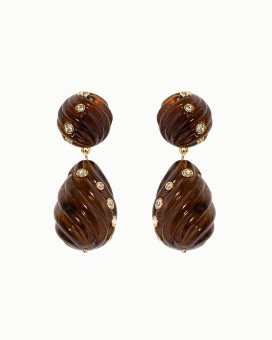 Pair of tortoise drop earrings with brown ridged oval pieces and small clear stones on a white background.