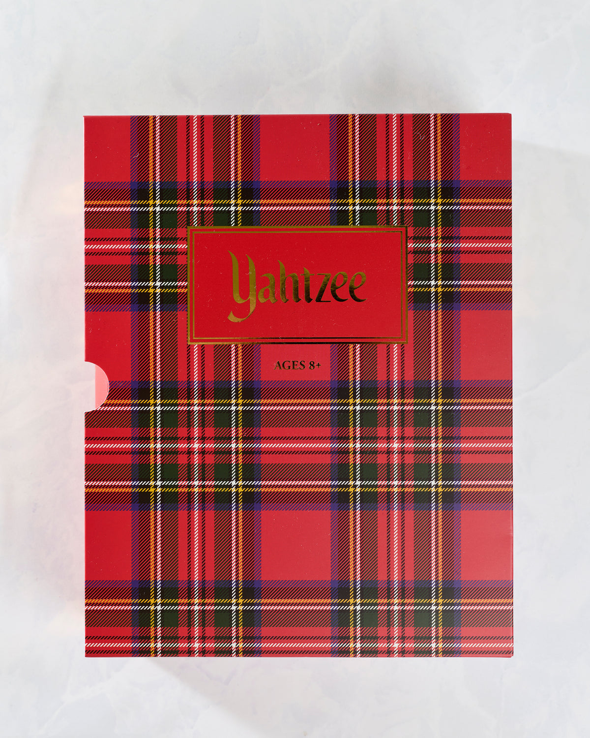 Front view of the red plaid Yahtzee Holiday Bookshelf Edition game case labeled Yahtzee and Ages 8+.