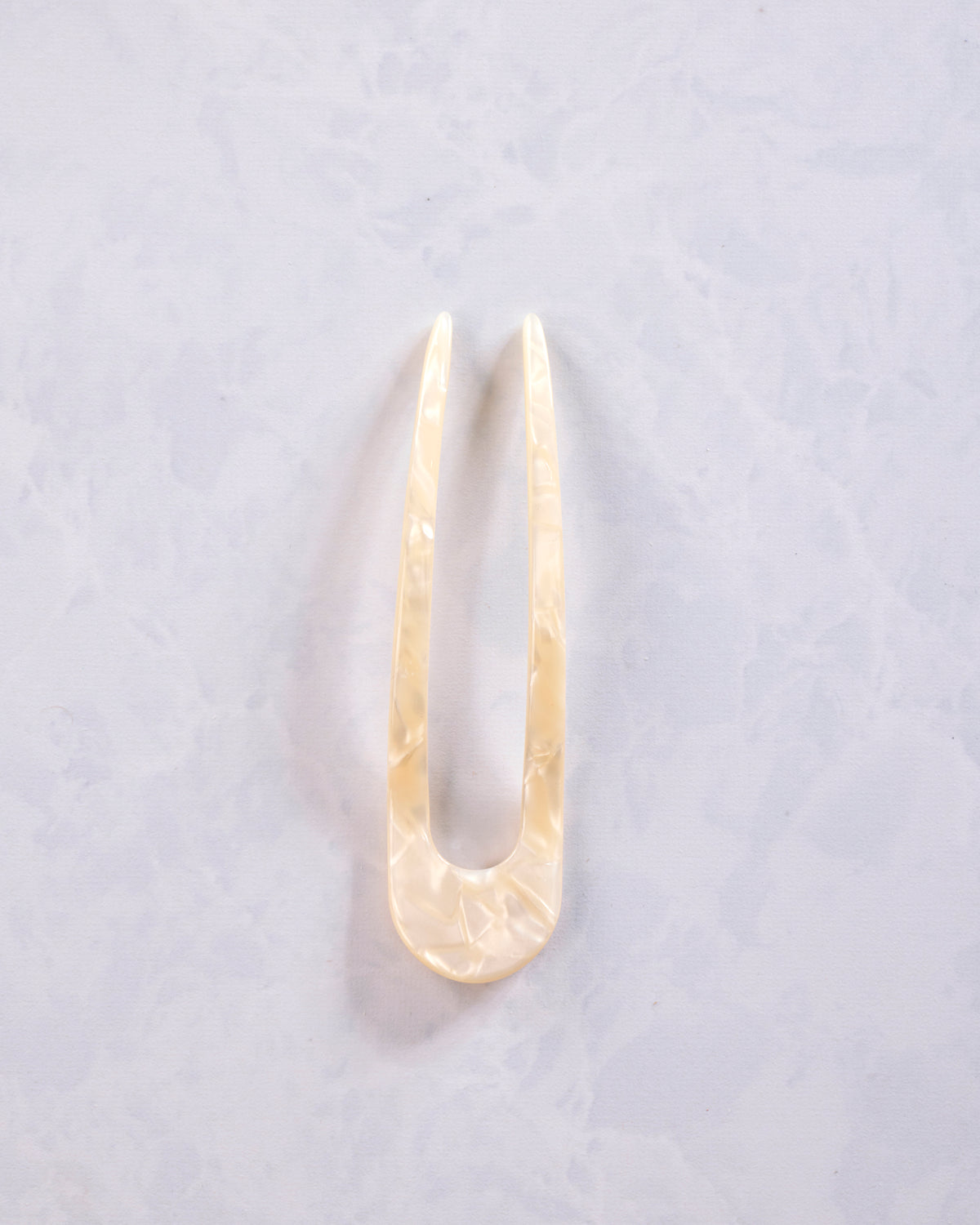 White shell French hair pin shown in full, with two long prongs and a rounded base.