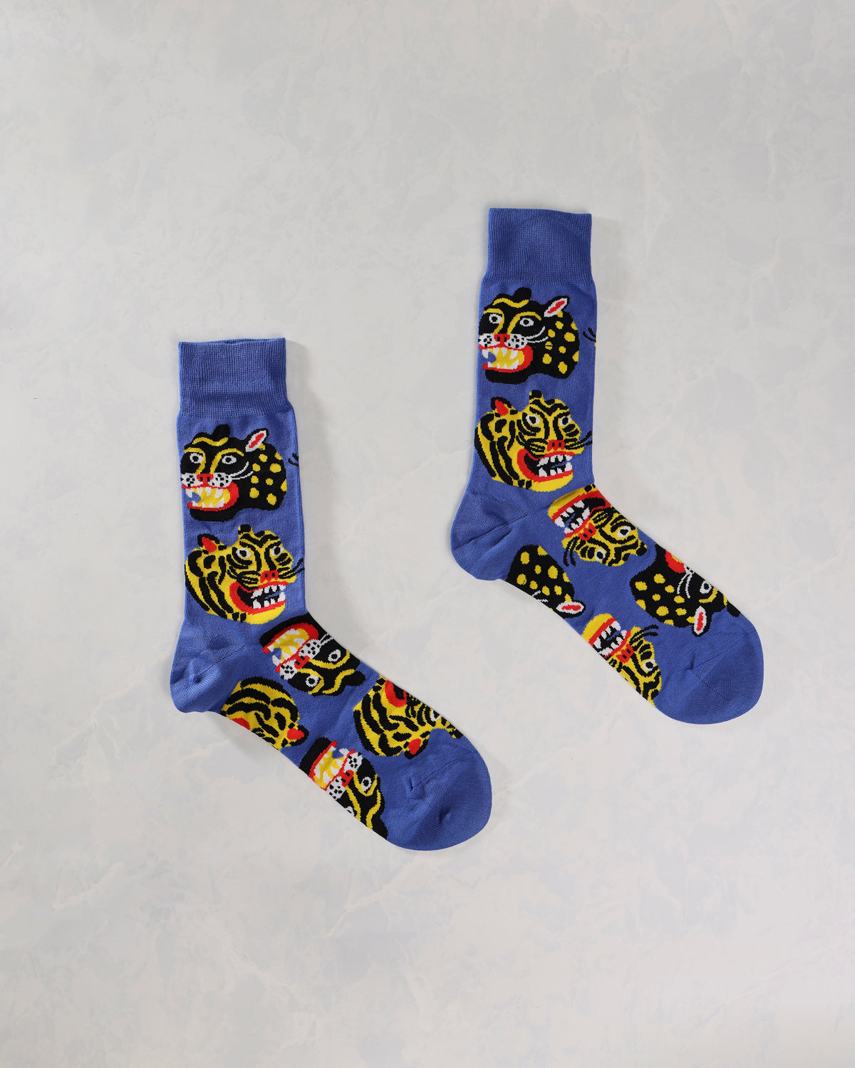 Pair of blue socks displayed separately with repeating black-and-yellow wild cat faces.