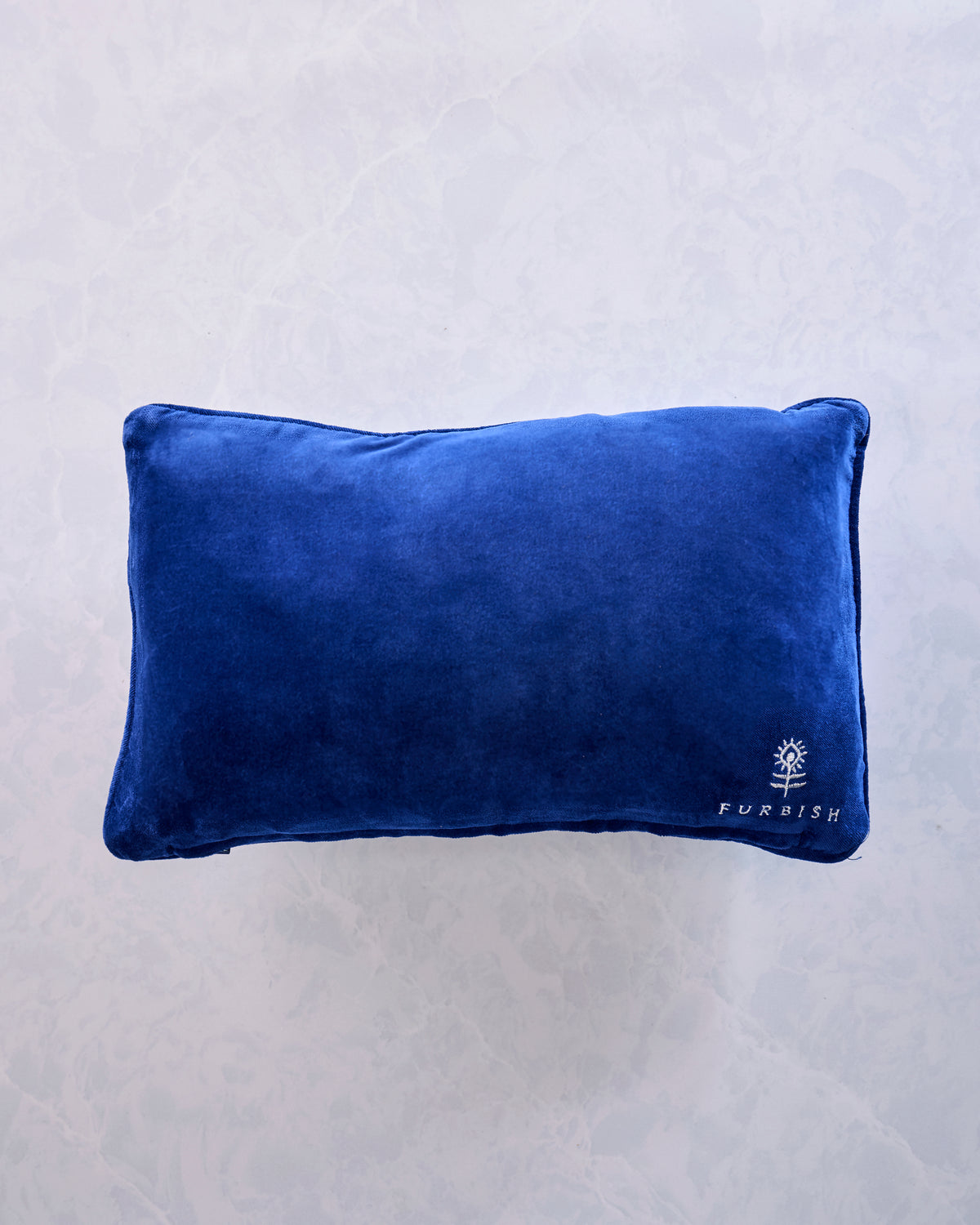 Blue velvet-backed needlepoint pillow shown from the back, with a Furbish logo embroidered in one corner.