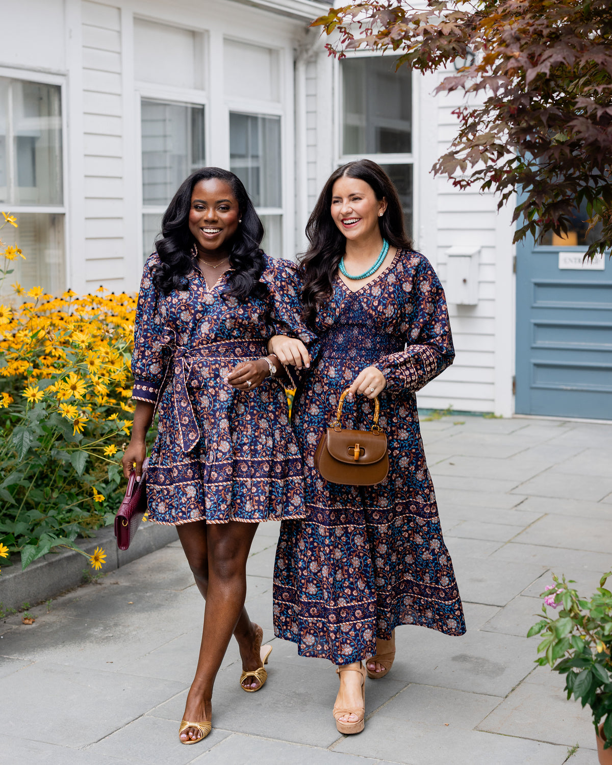 Valley Garden Romy dress in a dark floral print with a turquoise necklace and brown handbag, shown outdoors.