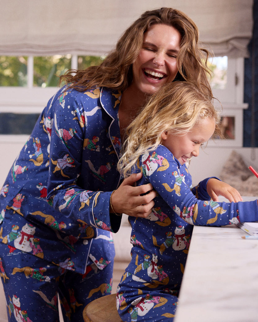 Adult and child wearing matching blue printed pajamas together beside a table.