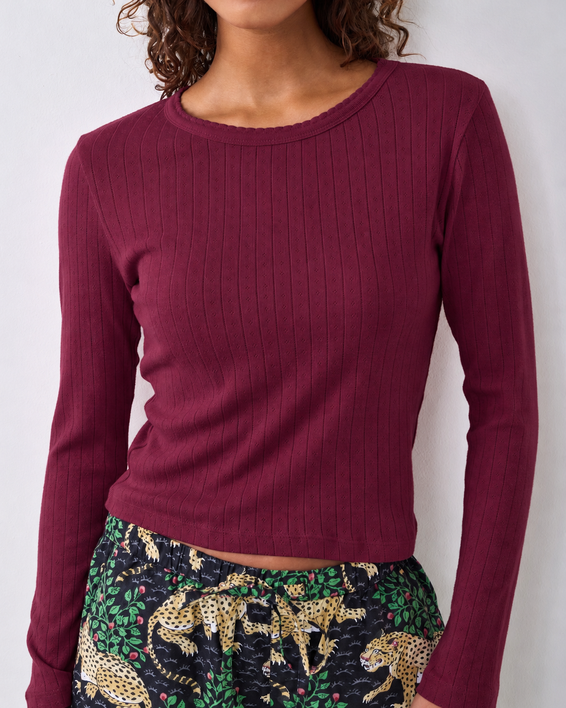 Wine-colored pointelle long-sleeve top with a scalloped neckline, worn with patterned pajama pants.