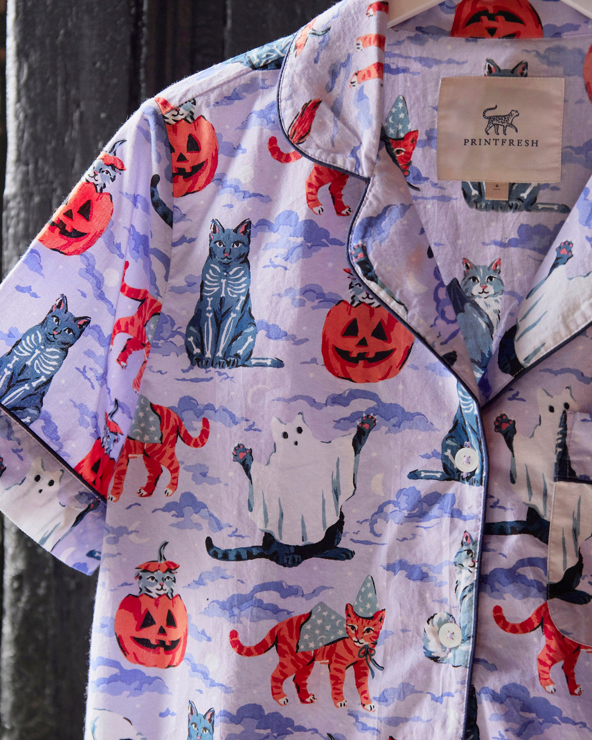 Halloween House Cats short pajama set with a lavender cat-and-ghost print, button-front top, notched collar, chest pocket, and matching shorts.