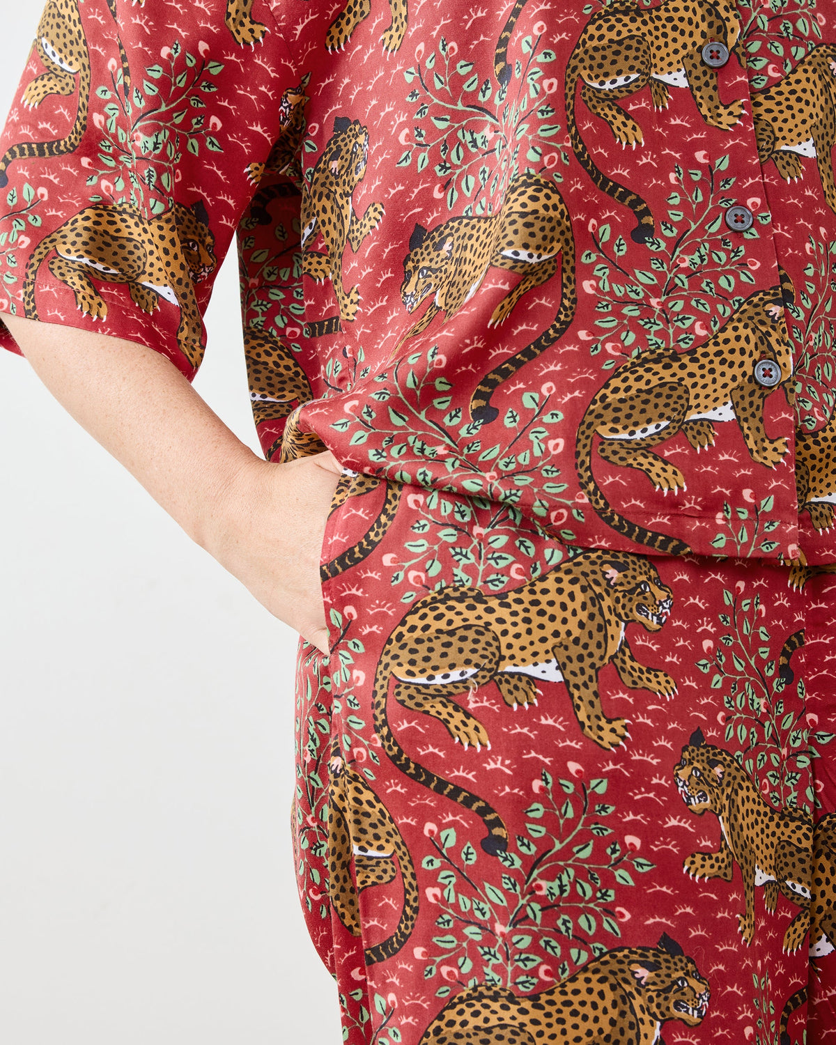 Close-up of the scarlet Bagheera pajama set showing the button-front top, short sleeves, side pocket, and leopard print.