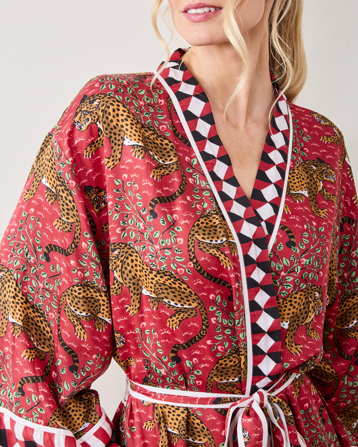 Close-up of the scarlet Bagheera robe showing the leopard print, geometric collar trim, white piping, and tie belt.