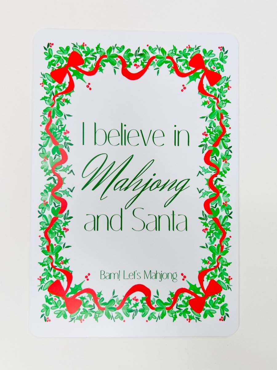 White Christmas Mahjong shuffler card with a leafy green and red ribbon border and the phrase “I believe in Mahjong and Santa.”
