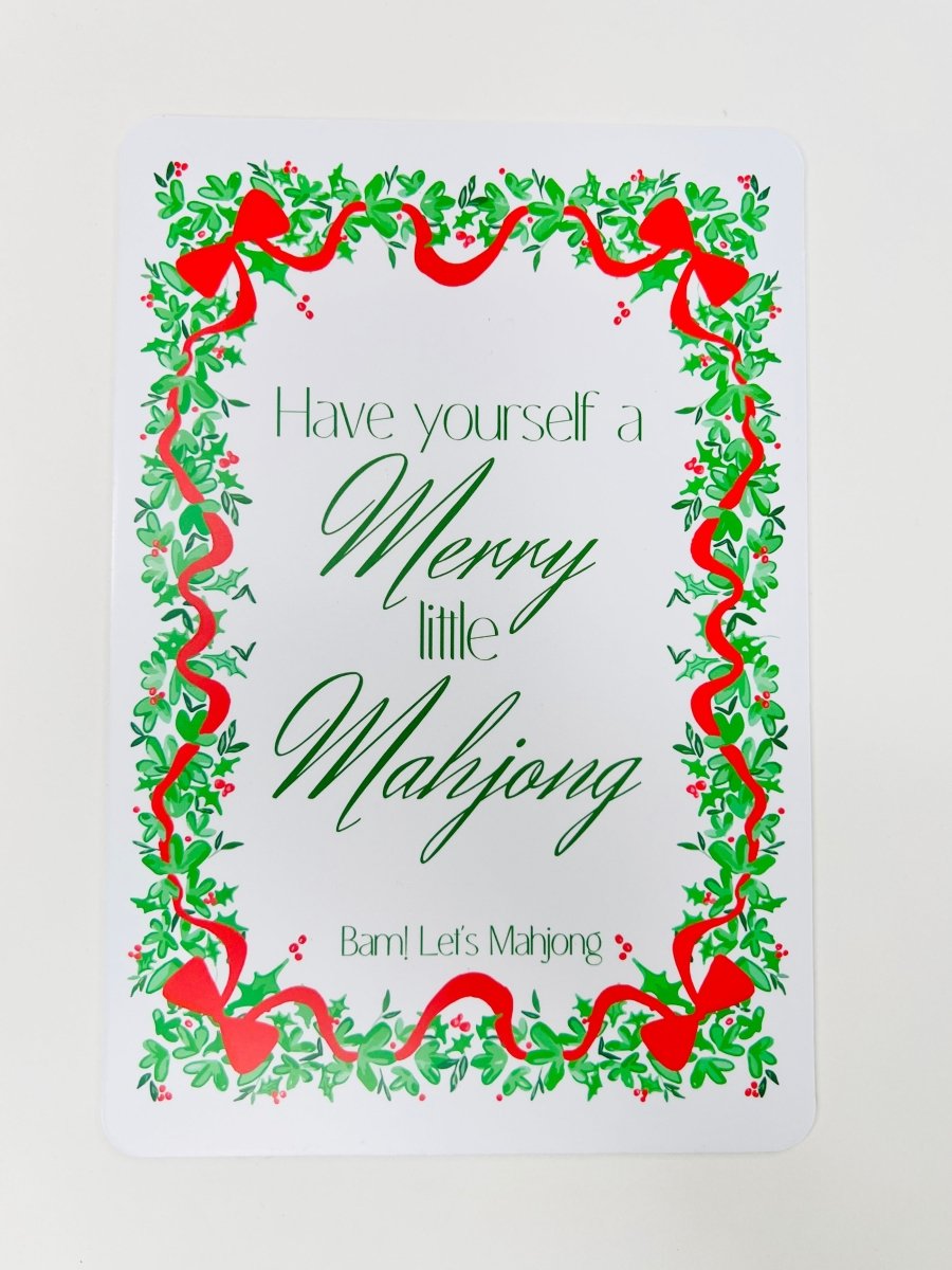 White Christmas Mahjong shuffler card with a leafy green and red ribbon border and the phrase “Have yourself a Merry little Mahjong.”