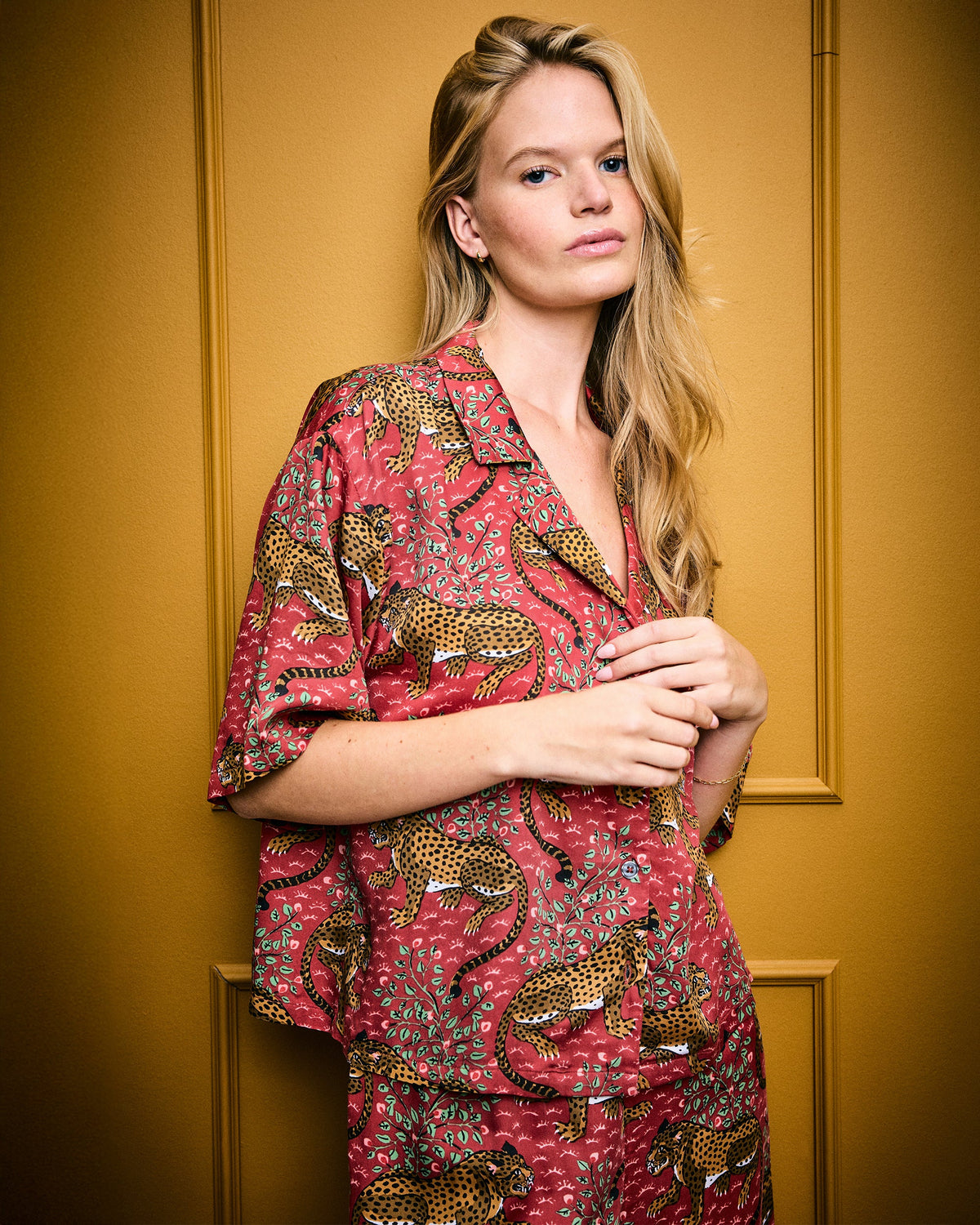 Close front view of a model wearing the scarlet Bagheera pajama top, showing the collar, button front, and leopard-and-leaf print.
