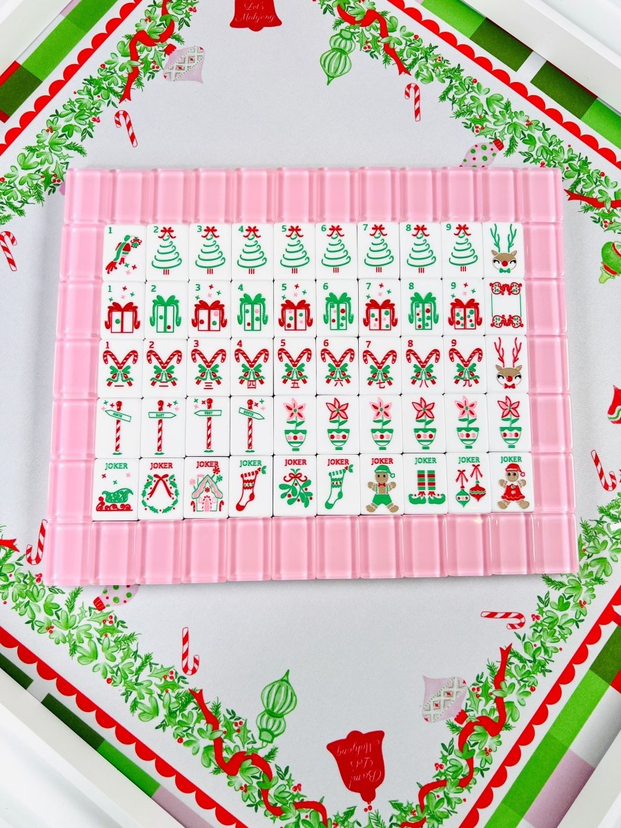 Overhead view of the complete Sugarplum Pink holiday mahjong tile set arranged in rows inside a pink tile rack, featuring numbered suits and joker tiles.