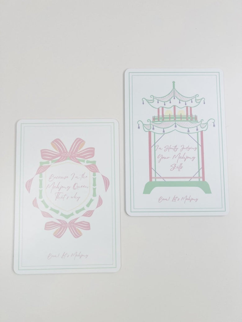 Two Mahjong tile shufflers shown together, one with a bow-and-wreath design and one with a carousel design, in pastel colors.