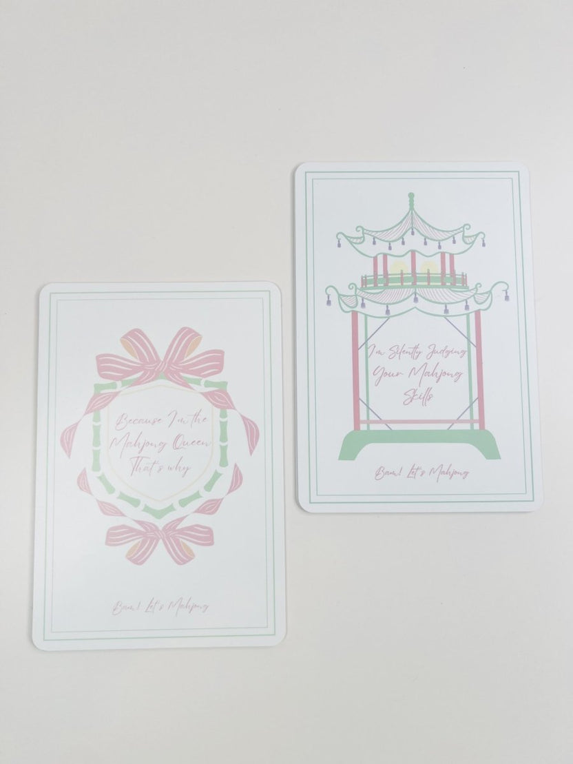 Two Mahjong tile shufflers shown together, one with a bow-and-wreath design and one with a carousel design, in pastel colors.