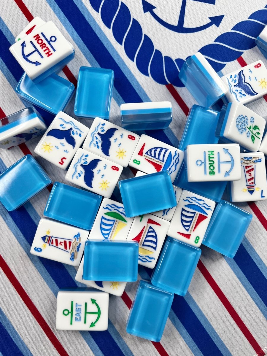 Nantucket Mahjong Mat beneath scattered blue-backed mahjong tiles, including tiles labeled North, South, and East.